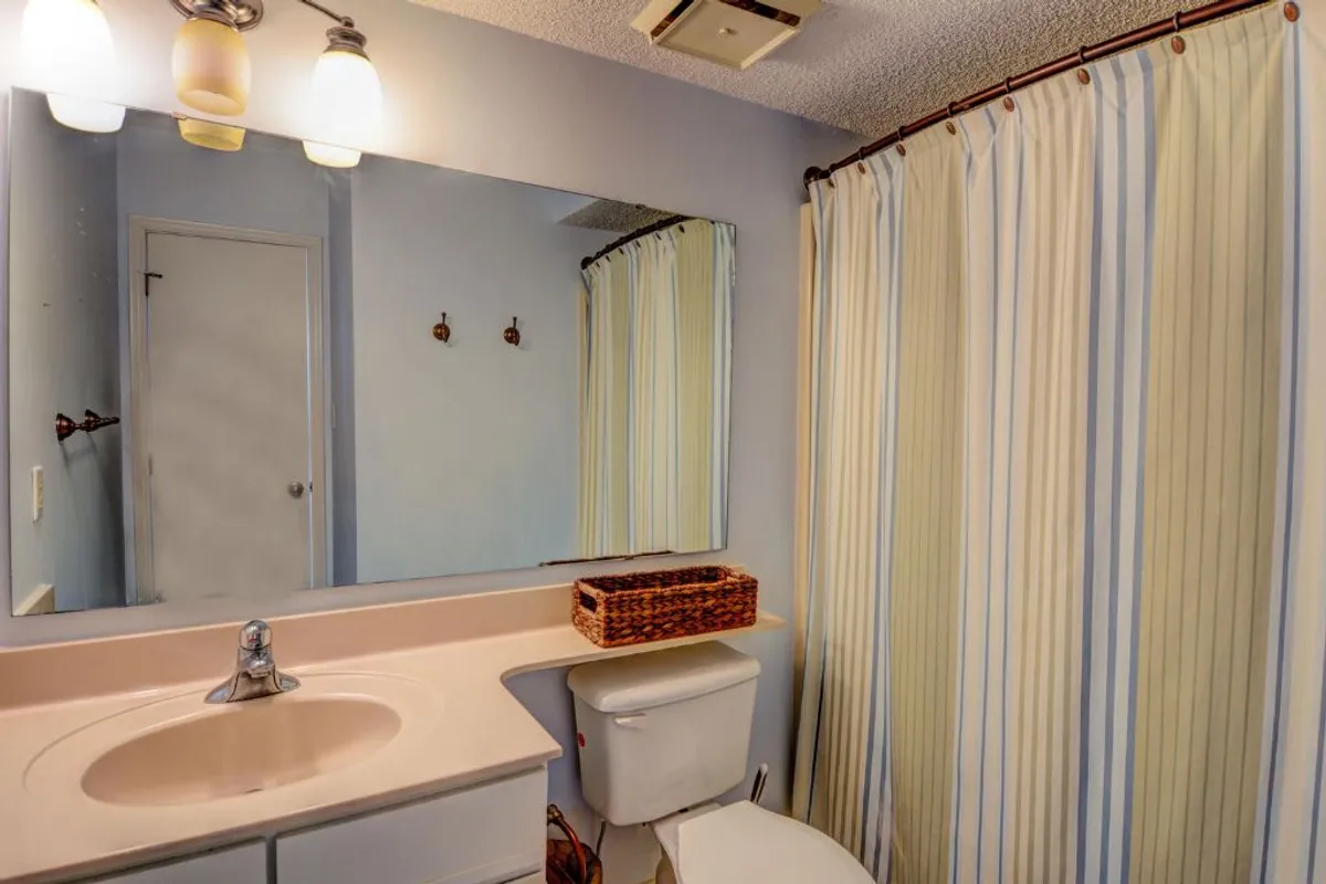 A bright, modern bathroom featuring a vanity with a mirror, sink, and a shower with a curtain. The space is clean, fresh, and designed for relaxation and self-care.