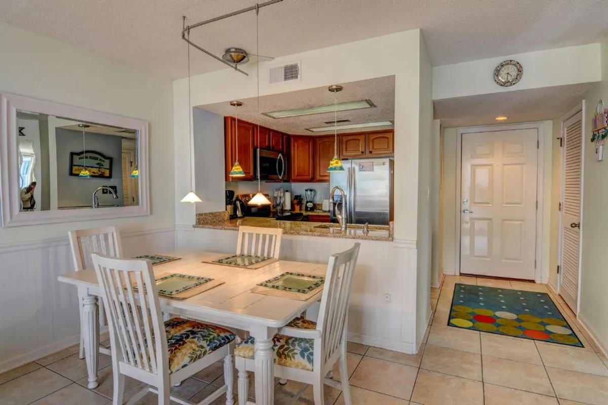 A warm, welcoming dining area seamlessly connected to the kitchen. The image includes a spacious dining table, kitchen countertop, pendant lights, and a wall mirror, inviting shared family meals and celebrations in a cozy atmosphere.
