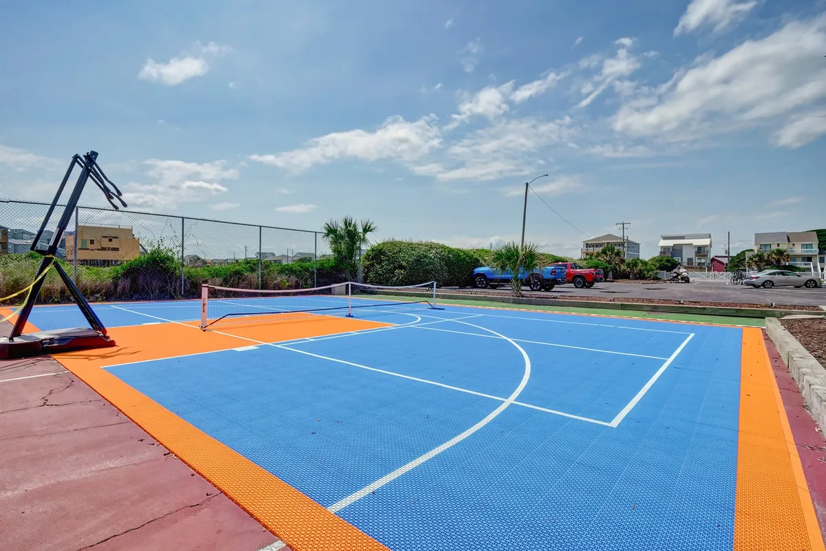 A colorful, energetic outdoor court equipped with a basketball hoop and tennis net, ideal for spirited games and casual hangouts. The space is designed for both competitive play and relaxed social gatherings, set against a fresh and lively backdrop.