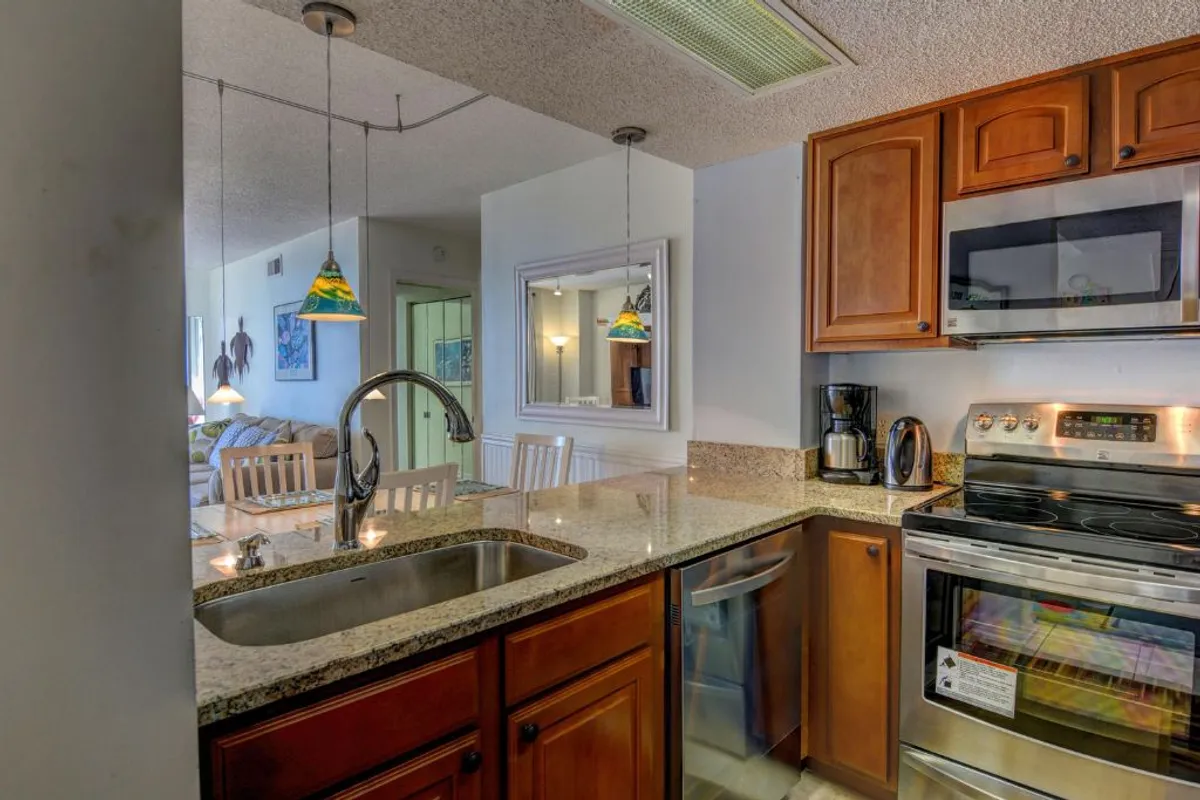 A modern kitchen featuring granite countertops, stainless steel appliances, and colorful pendant lights. The layout is open and inviting, with everything at arm’s reach for easy meal prep and entertaining. High-quality finishes create a polished, fresh look that inspires culinary creativity.