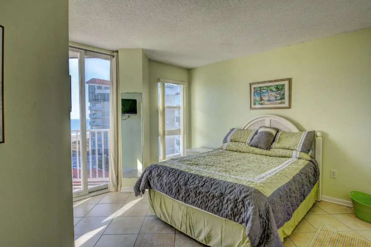 A cozy bedroom featuring a bed with decorative bedding, large windows that let in natural light, and tasteful artwork on the wall. The inviting space feels freshly updated and ideal for relaxing after a long day.